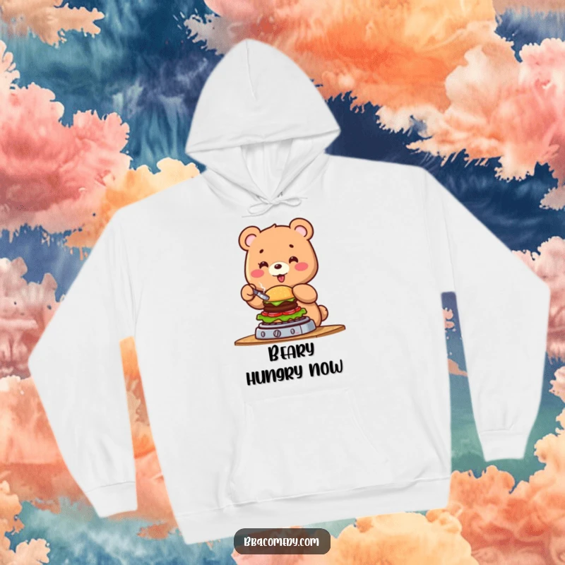 Funny cheerful bear flipping a tiny burger on a grill, depicted on a warm and humorous hoodie.