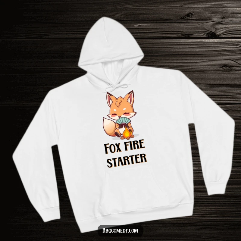 Funny determined fox fanning embers with a small fan, depicted on a warm and humorous hoodie.